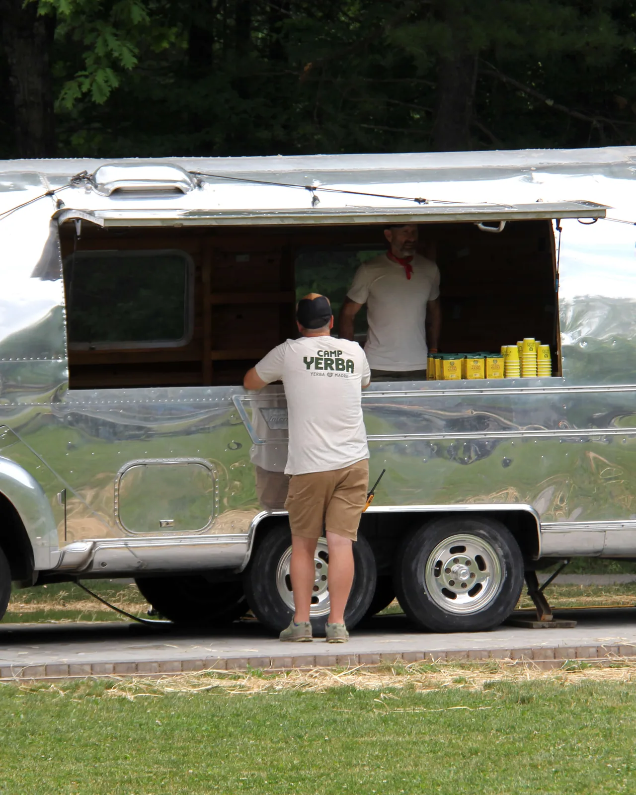 Camper at a silver Airstream bar trailer in a Camp Yerba t-shirt