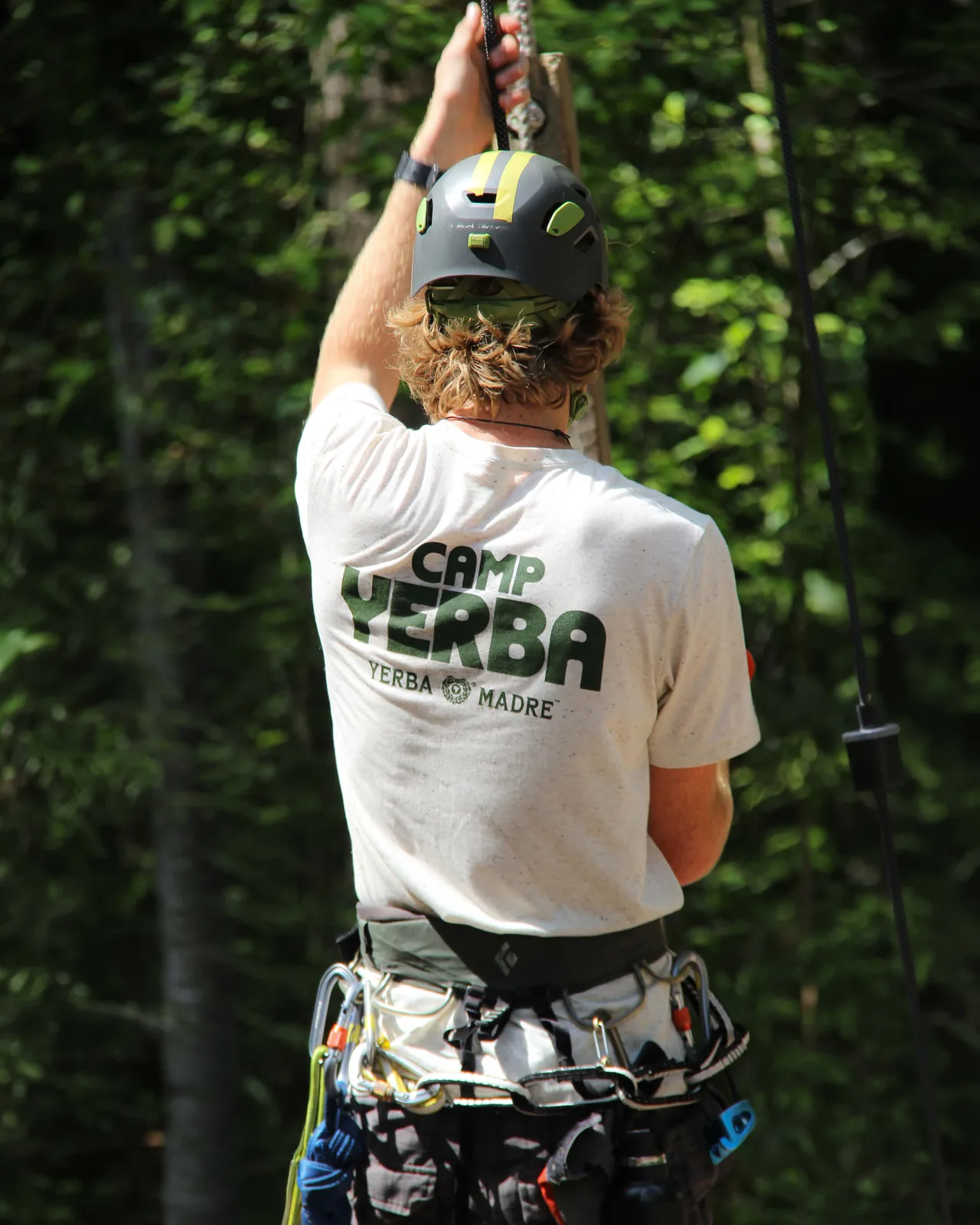 Camper on a zipline in a white Camp Yerba t-shirt