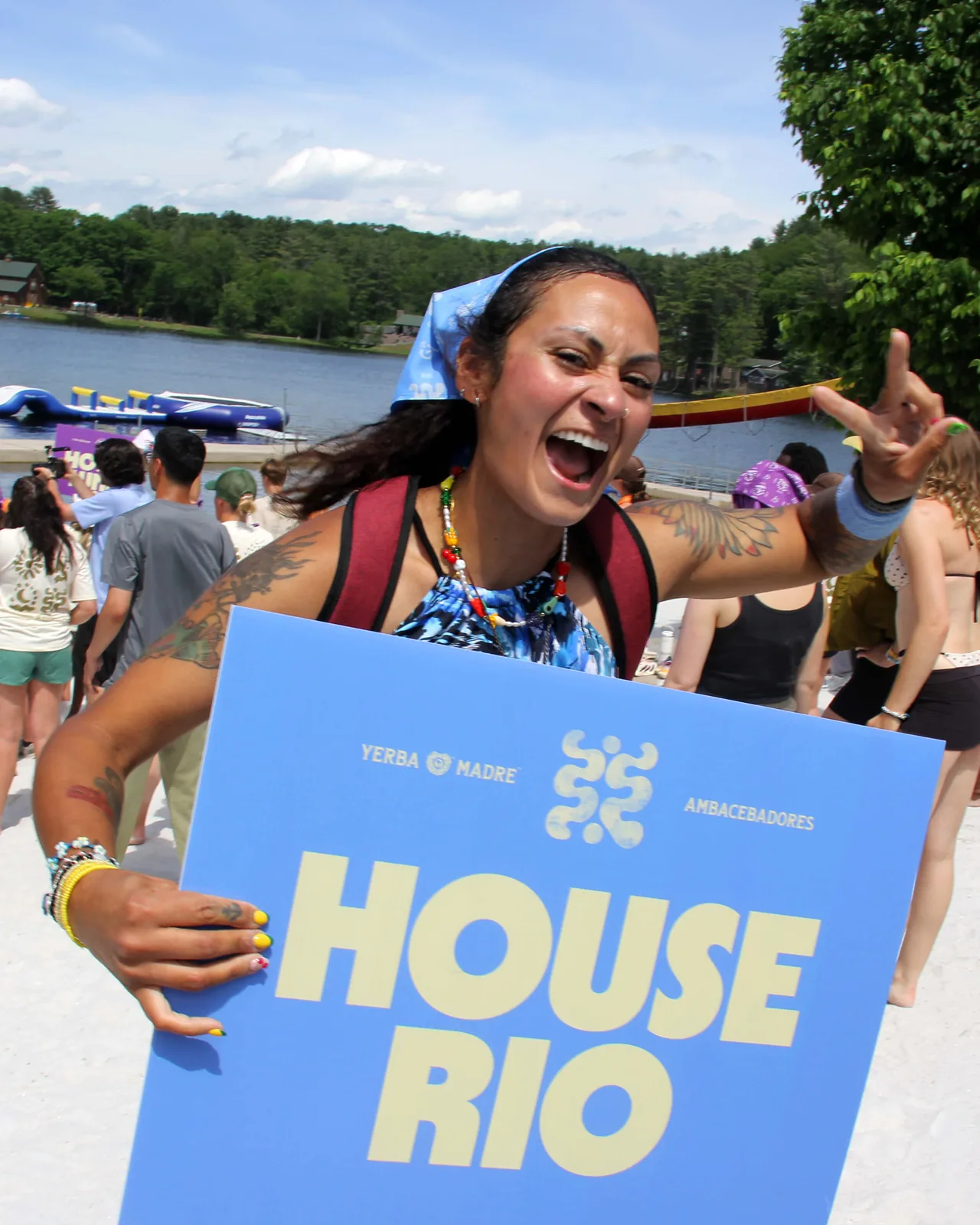 Camper cheering with a blue House Rio placard by the lake