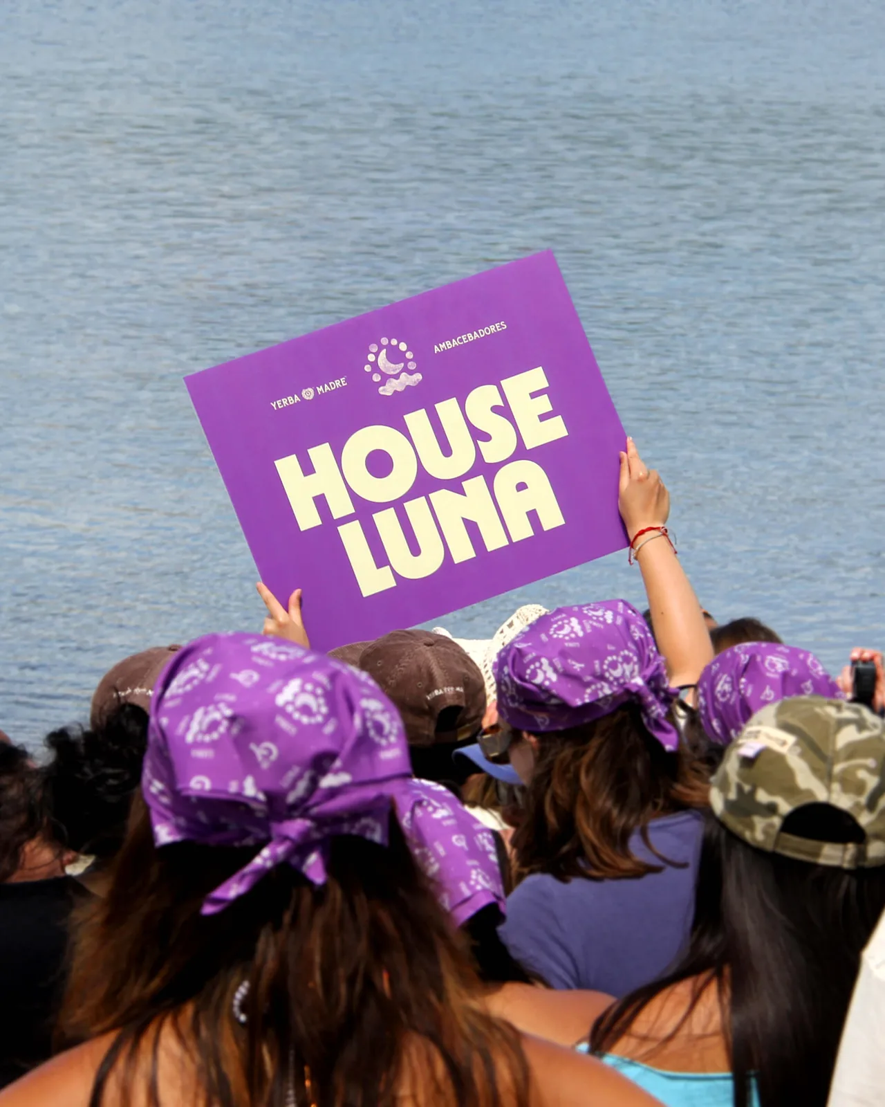 Purple House Luna placard over campers in purple bandanas by the lake