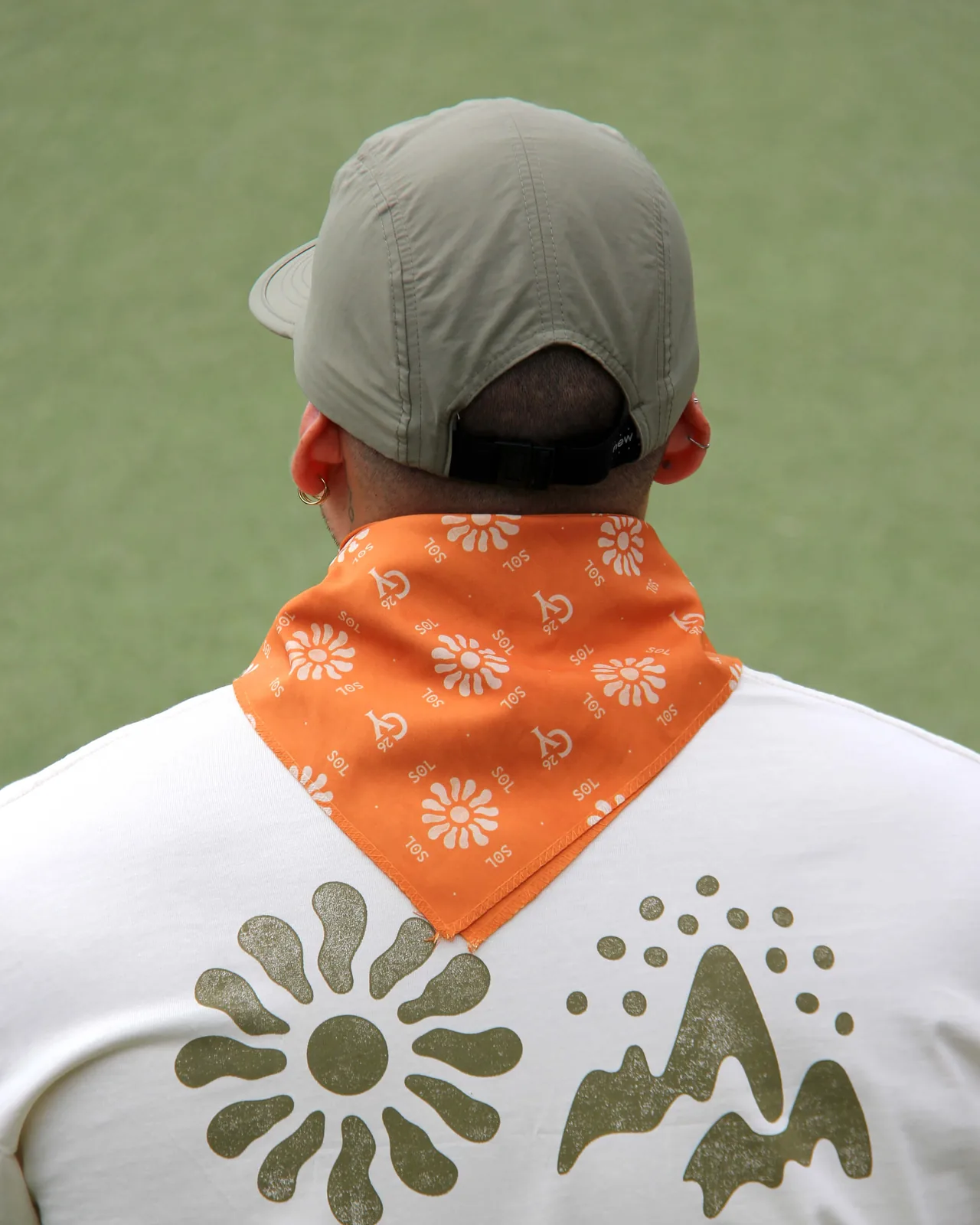 Orange House Sol bandana over a white tee printed with the sun and mountain icons