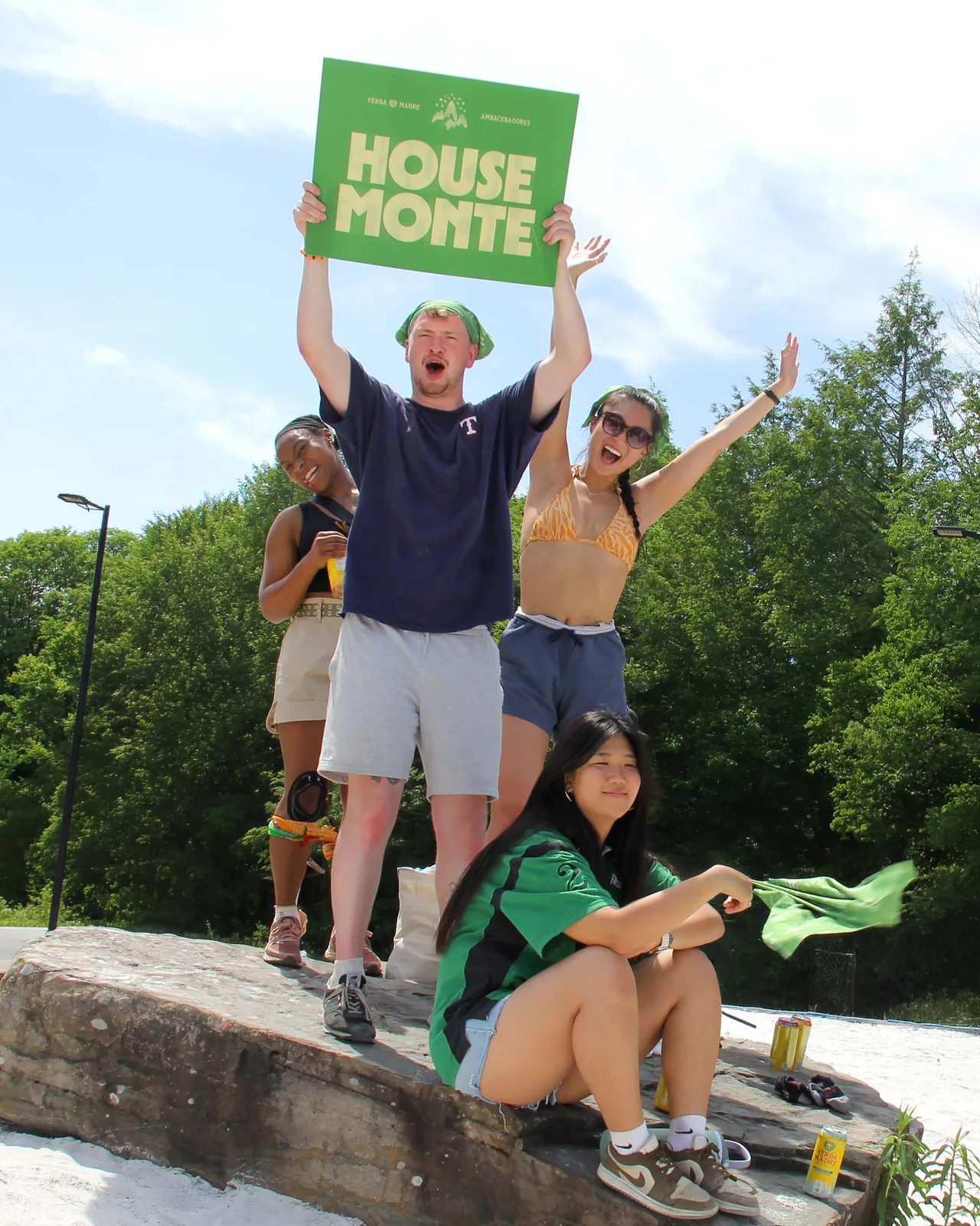 Campers on a rock holding up a green House Monte sign