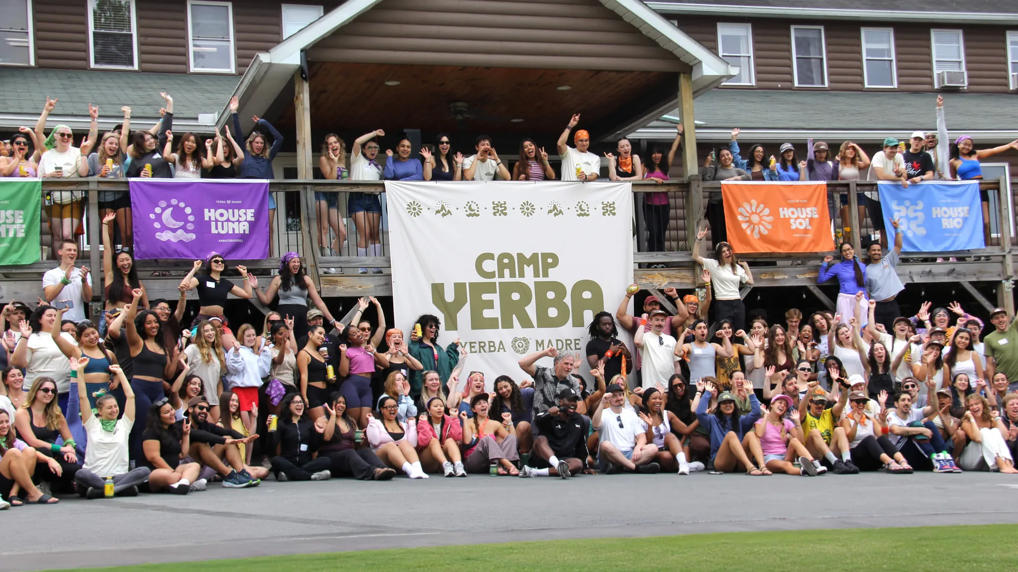 Camp Yerba campers gathered in front of the lodge with the house banners