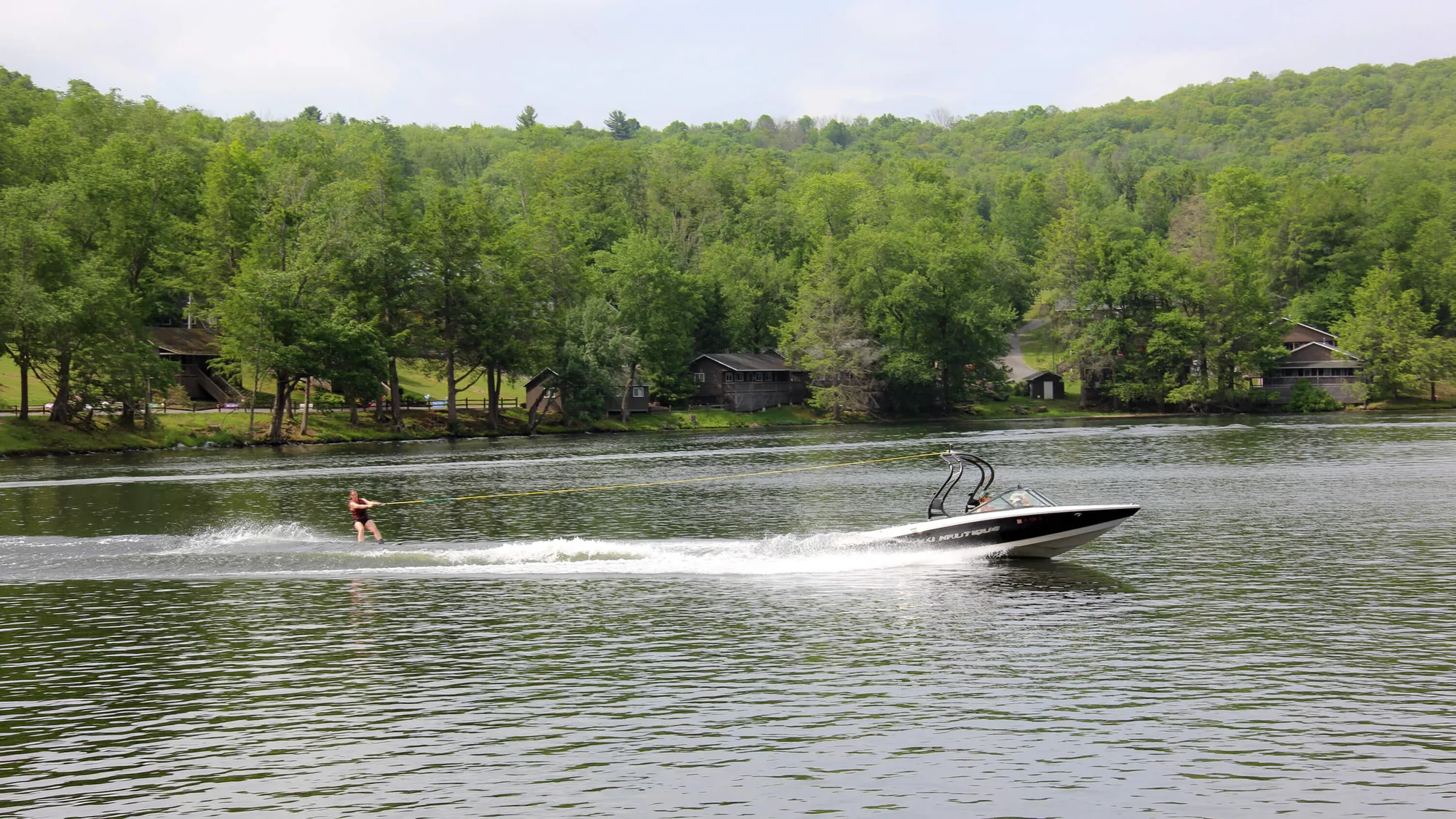 Speedboat pulling a water skier across the lake at camp