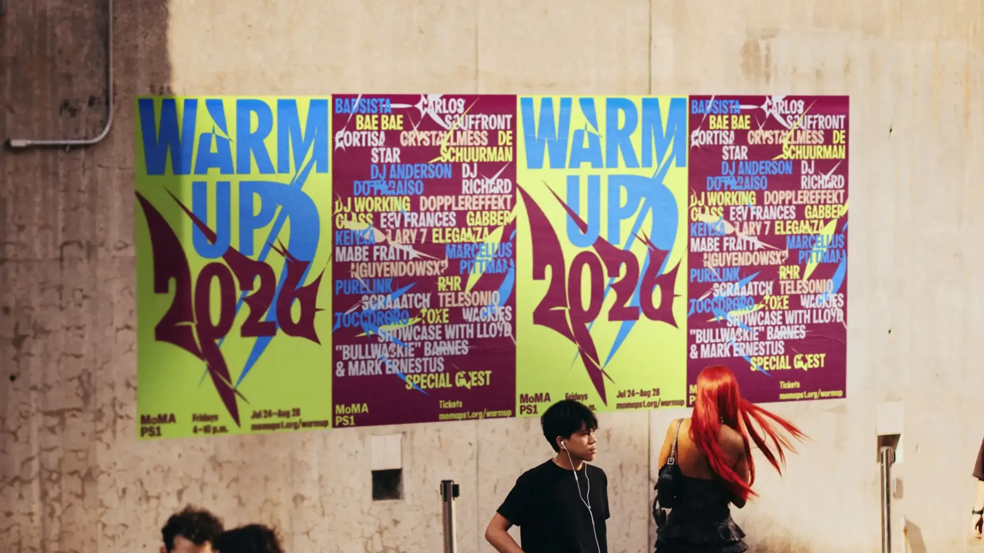 Warm Up 2026 posters pasted on a concrete wall with passers-by