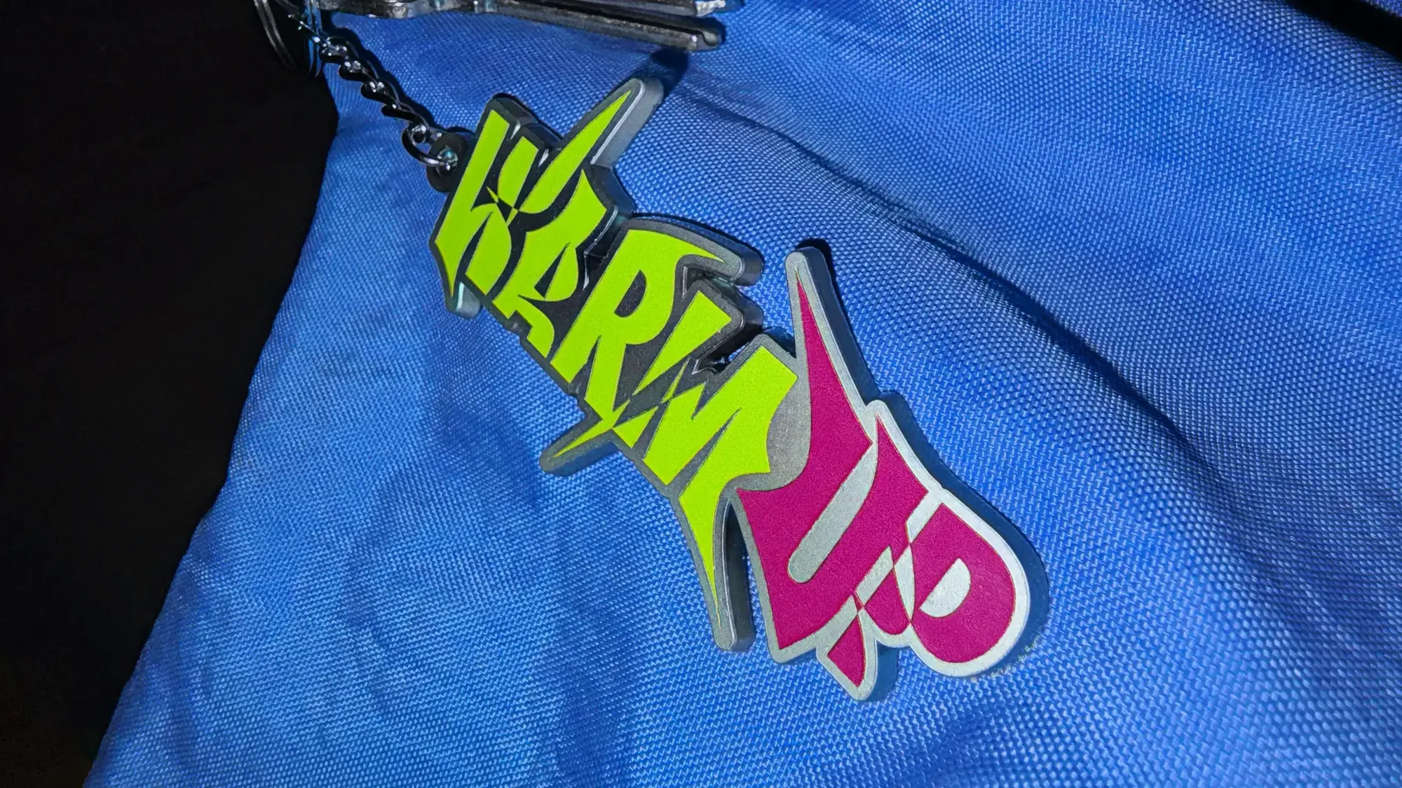 Warm Up keychain in lime and pink on a blue bag