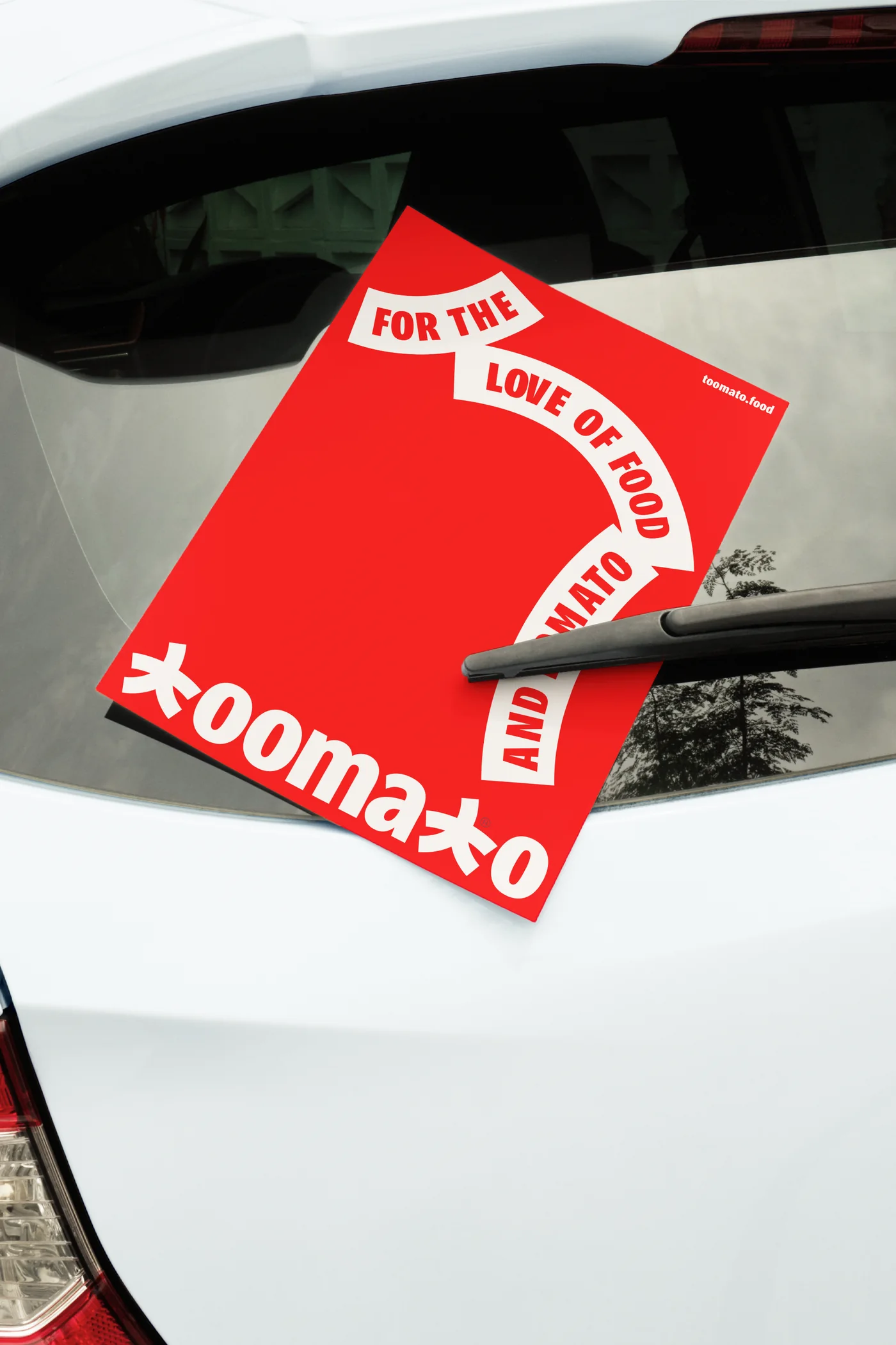 Toomato flyer tucked under a car windscreen wiper