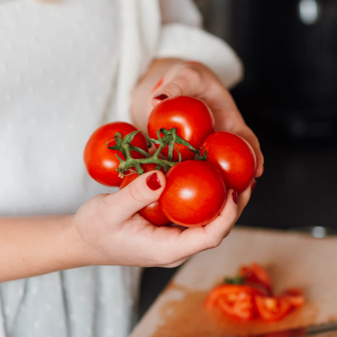 Hands holding a bunch of ripe tomatoes on the vine