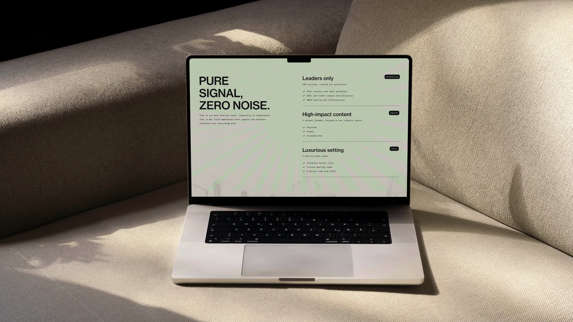 Laptop on a sofa showing the Yield website, Pure signal, zero noise, on sage green